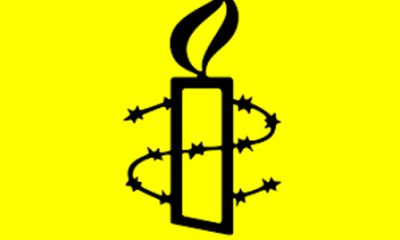 Logo van Amnesty; een kaars met prikkeldraad er omheen