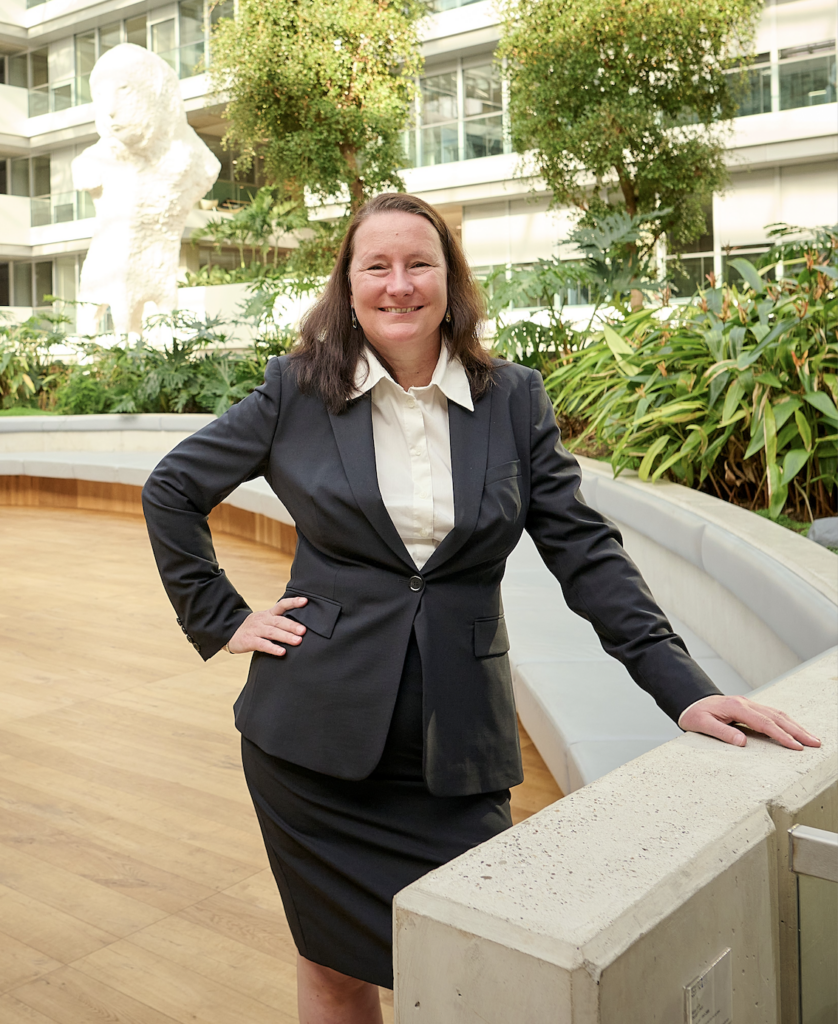 Foto Tanja van Burgel, voorzitter aanjaagteam, staand, in een open ruimte, met hand op een reling