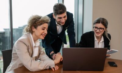 Drie collega's overleggen voor een laptop in een kantoor.
